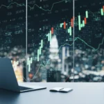 An open laptop and notebook are seen on a desk next to a mug. Behind the desk is a large window with a financial trading chart displayed across it.