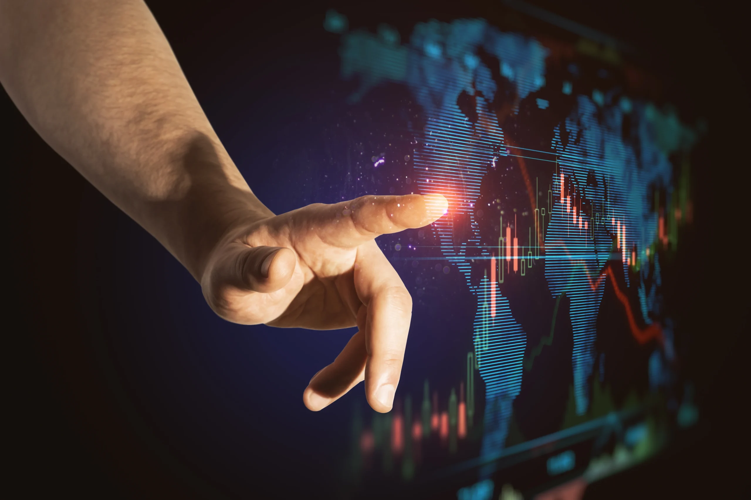 A disembodied hand is seen touching a glowing spot on a digital world map, with financial graphs displayed. The map features blue lines and red financial charting that suggests a futuristic, technology-driven environment. The background is a dark blue with a high contrast with shadows.