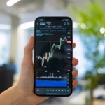 A person holding a smartphone displaying a cryptocurrency chart in an office setting