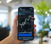 A person holding a smartphone displaying a cryptocurrency chart in an office setting
