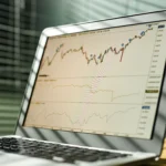 Close-up-of-a-laptop-displaying-stock-market-data-and-graphs-in-an-office-setting
