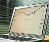 Close-up-of-a-laptop-displaying-stock-market-data-and-graphs-in-an-office-setting