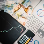 Overhead-view-of-financial-tools-with-Euro-banknotes-on-a-desk-showing-market-trends-and-graphs