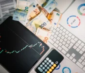 Overhead-view-of-financial-tools-with-Euro-banknotes-on-a-desk-showing-market-trends-and-graphs