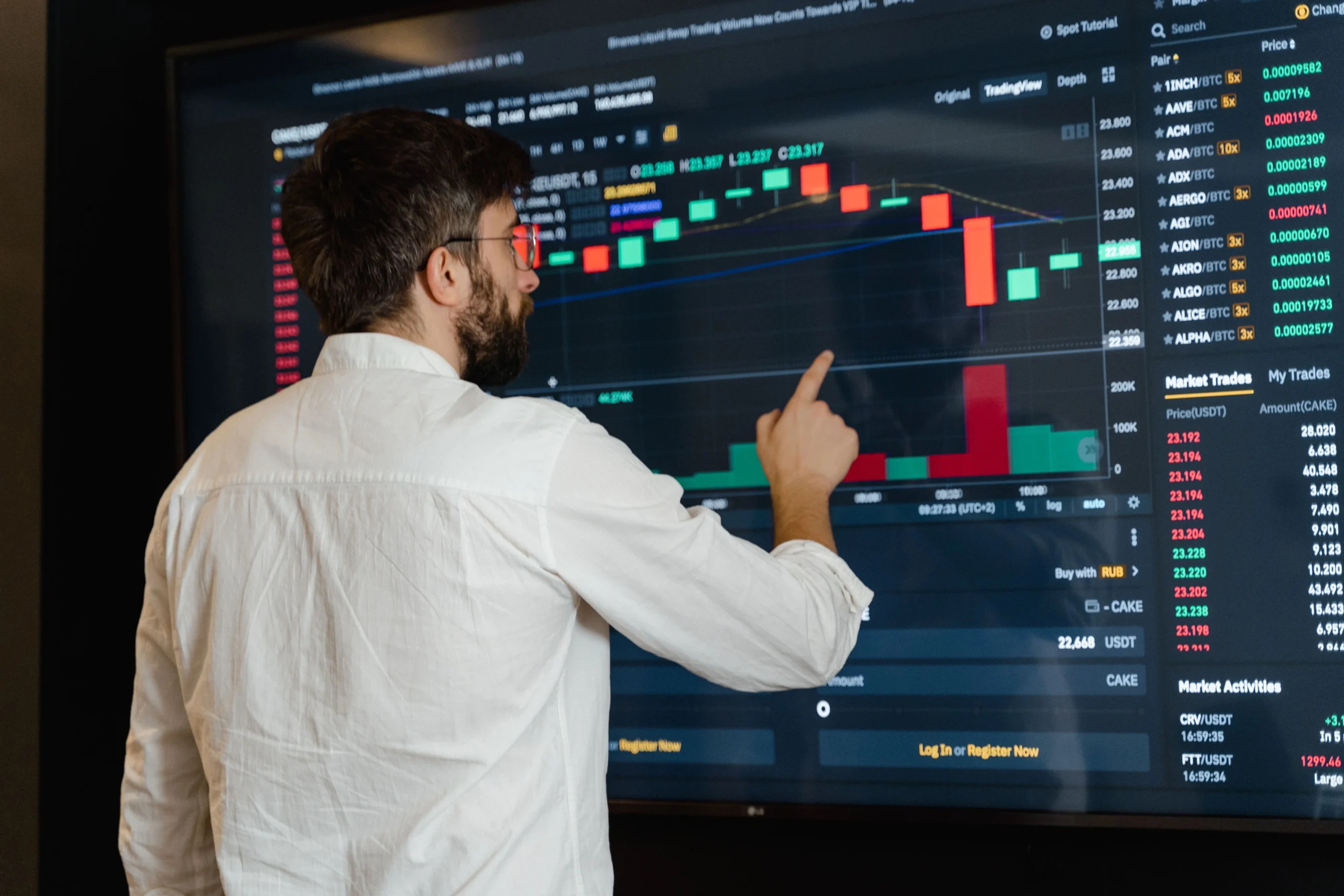 A man analyzes cryptocurrency graphs on a touchscreen monitor in a modern office setting